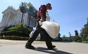 California’s Plastic-Bag Ban Put On Hold By Ballot Referendum 1 man_carries_plastic_single_use_bags_past_the_Capitol_in_Sacramento